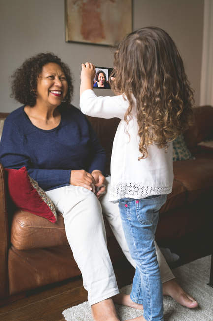 Дівчина фотографує бабусю на мобільному телефоні вдома — стокове фото