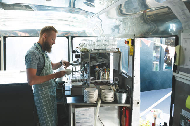Vista lateral del camarero preparando café en camión de comida - foto de stock