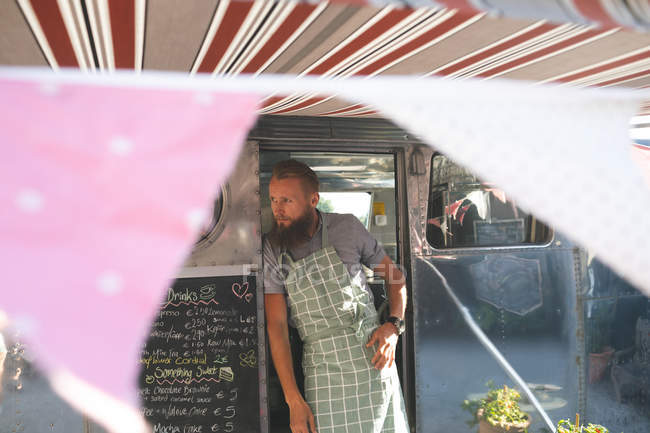 Thoughtful male waiter standing on food truck — Stock Photo