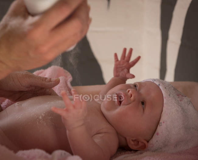 Primer plano de la madre aplicando talco para su bebé después del baño - foto de stock
