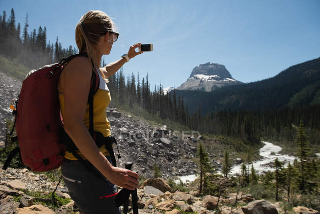 Жіночий пішохід, що бере селфі з мобільним телефоном в горах — стокове фото