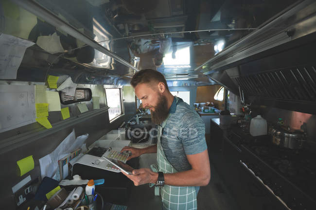Waiter using digital tablet while operating billing machine in food truck — Stock Photo