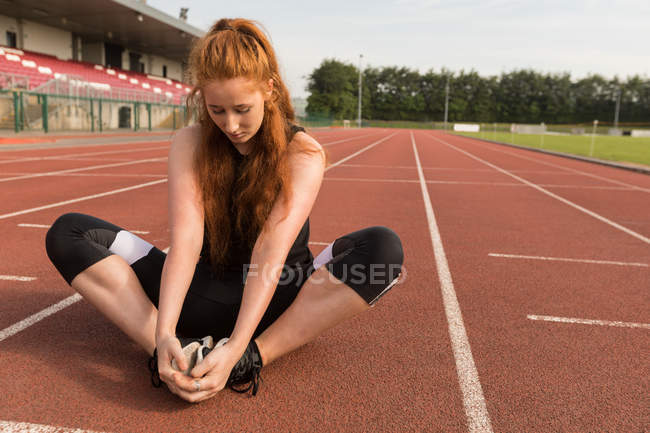 Jeune athlète féminine faisant de l'exercice sur piste — Photo de stock