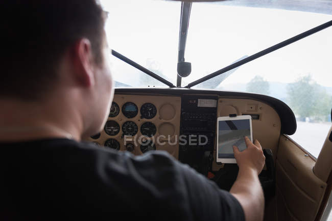 Вид ззаду пілота за допомогою цифрового планшета в кабіні — стокове фото