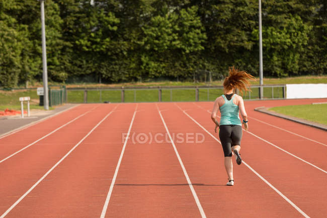Visão traseira do atlético feminino correndo em pista de esportes — Fotografia de Stock