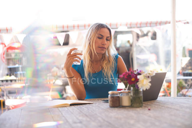 Красива жінка використовує ноутбук у відкритому кафе — стокове фото