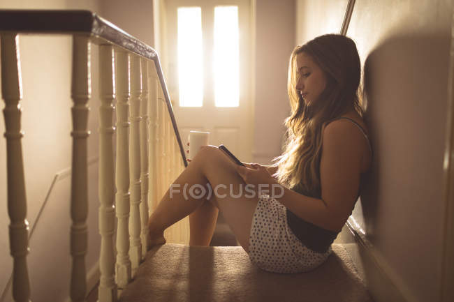 Frau benutzte Handy in der Nähe von Treppen zu Hause — Stockfoto