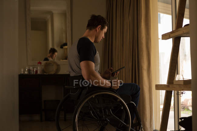 Инвалид, использующий мобильный телефон дома — стоковое фото