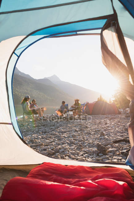 Grupo de amigos acampando cerca de la orilla del río en un día soleado - foto de stock