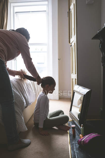 Madre sta facendo un'acconciatura per sua figlia a casa — Foto stock