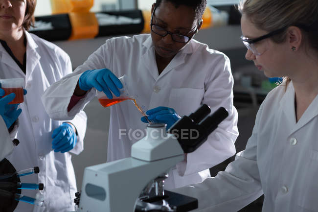 Equipo de científicos experimentando juntos en laboratorio - foto de stock