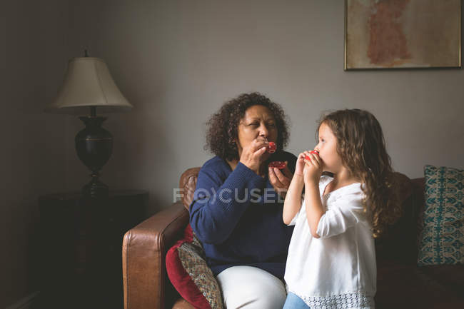 Little girl playing with grandmother on sofa at home — Stock Photo
