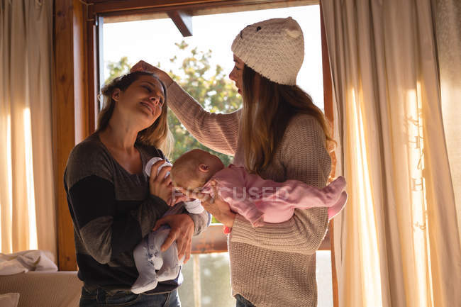 Lesbian couple holding their babies at home — Stock Photo