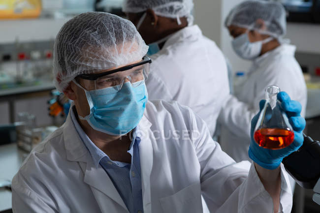 Hombre científico sosteniendo matraz en laboratorio - foto de stock