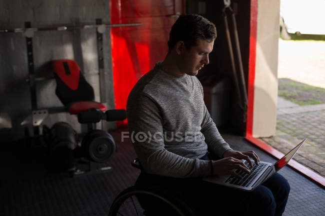Молодой инвалид с ноутбуком в мастерской — стоковое фото