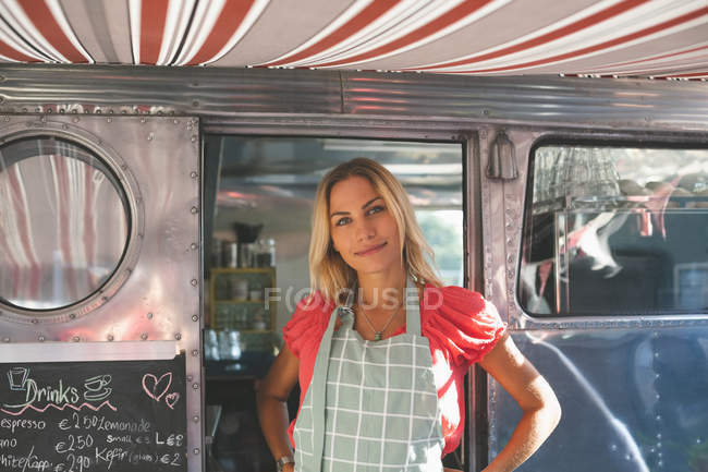 Hermosa camarera femenina de pie en camión de comida - foto de stock