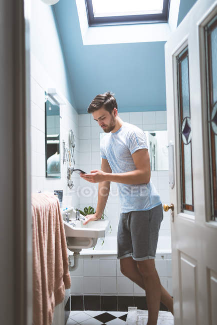 Чоловік використовує мобільний телефон у ванній вдома — стокове фото