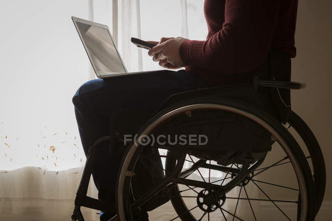Mittlerer Abschnitt behinderter Mann nutzt Handy zu Hause — Stockfoto