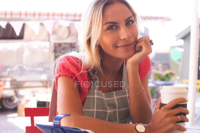 Portrait of female waitress having coffee in outdoor cafe — Stock Photo