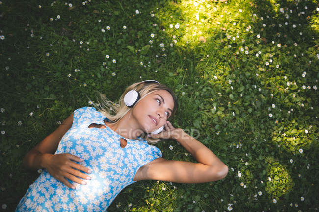 Hermosa mujer escuchando música en el jardín - foto de stock