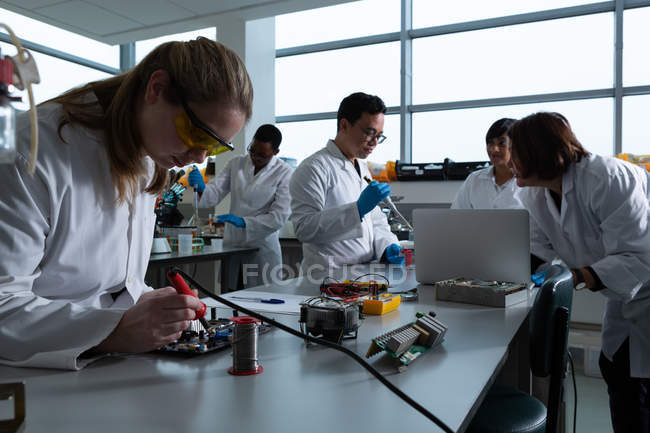 Wissenschaftlerin lötet Leiterplatte im Labor — Stockfoto