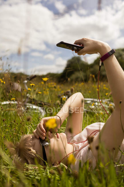 Woman listening music on mobile phone in the field — Stock Photo
