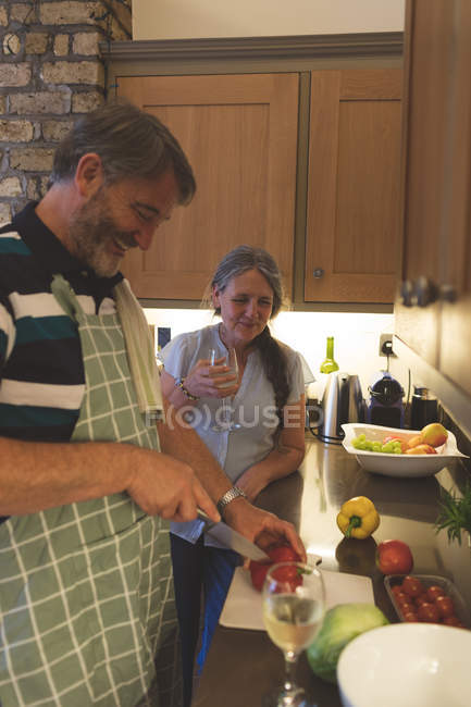 Casal sênior cortando vegetais na cozinha em casa — Fotografia de Stock