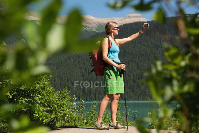Escursionista femminile scattare selfie con il telefono cellulare in montagna — Foto stock