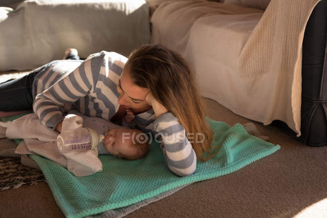 Alimentazione madre con bottiglia di latte sul pavimento a casa — Foto stock