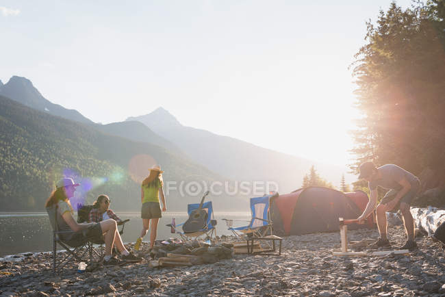 Gruppe von Freunden zeltet an einem sonnigen Tag in der Nähe des Flusses — Stockfoto