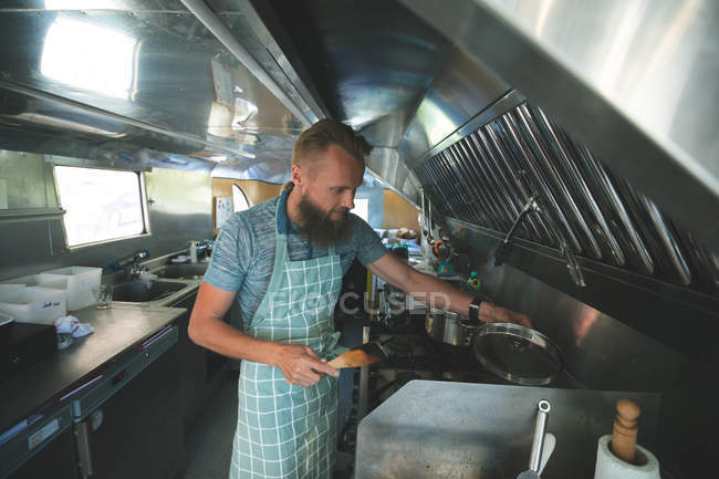 Camarero guapo preparando comida en camión de comida - foto de stock