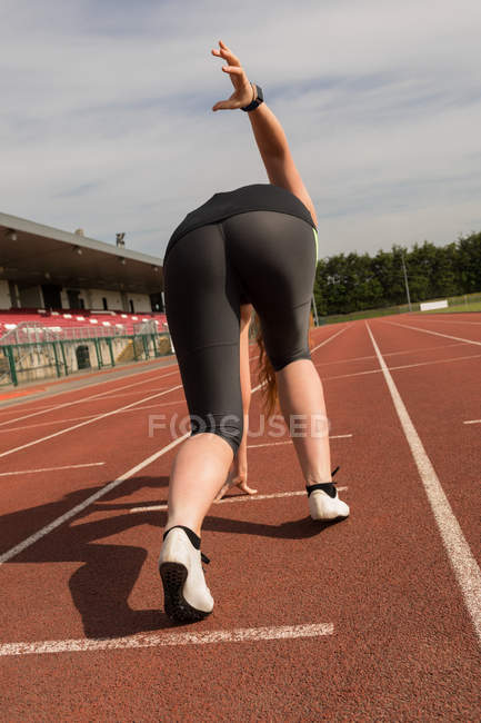 Vue arrière de la course sportive féminine sur piste de sport — Photo de stock