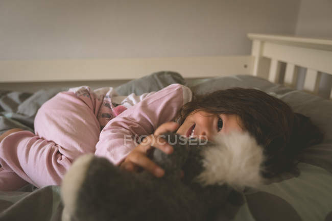 Дівчинка, граючи з ведмедиком на ліжку у себе вдома — стокове фото