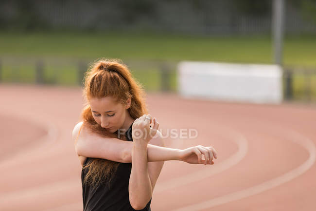 Jeune athlète féminine faisant de l'exercice sur piste — Photo de stock