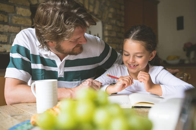 Father helping her daughter in studies at home — Stock Photo