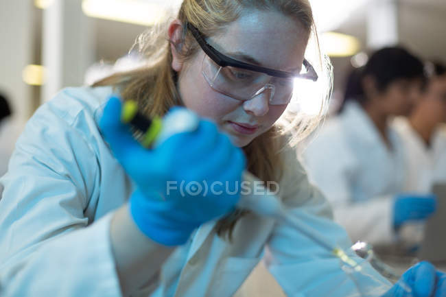 Крупный план женщины-ученого с использованием пипетки в лаборатории — стоковое фото