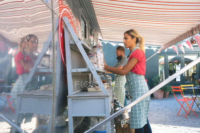 Pareja trabajando cerca de camión de comida juntos - foto de stock