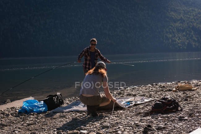 Пара встановлює намет біля берега річки — стокове фото