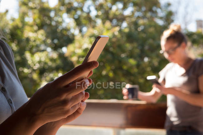 Лесбійську пару, що використання мобільного телефону у балкон вдома — стокове фото