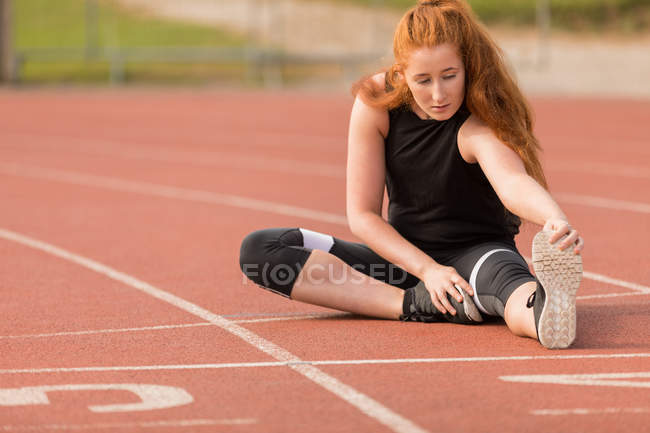 Giovane atletica femminile che esercita sulla pista da corsa — Foto stock
