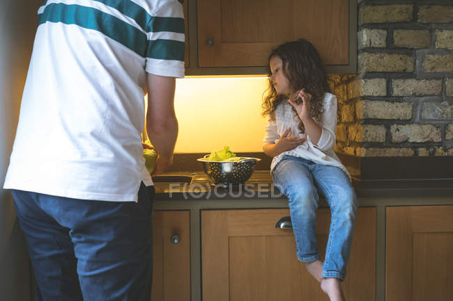 Padre lavado de verduras con hija en la cocina en casa - foto de stock