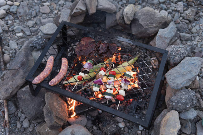 Calefacción de alimentos en una barbacoa en el camping - foto de stock