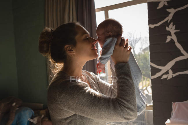 Mãe brincando com bebê perto da janela em casa — Fotografia de Stock