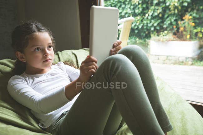 Chica usando tableta digital en la sala de estar en casa - foto de stock