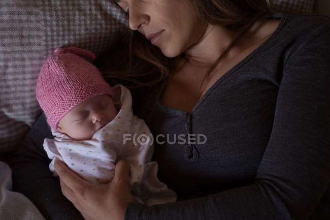 Primer plano de la madre con el bebé relajándose en la cama en casa - foto de stock