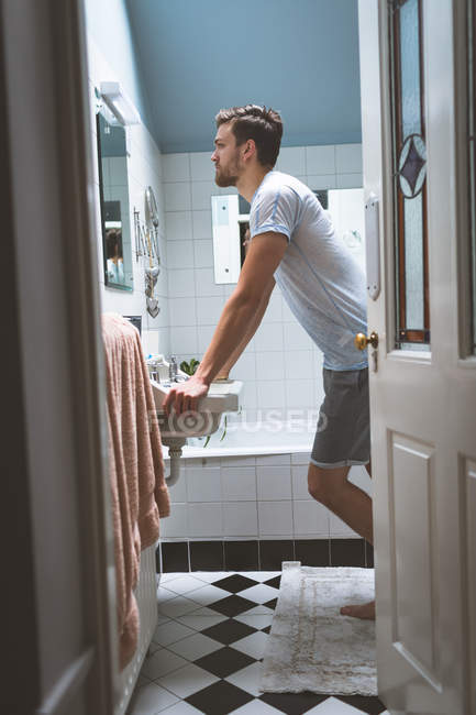Jeune homme regardant dans le miroir à la maison — Photo de stock