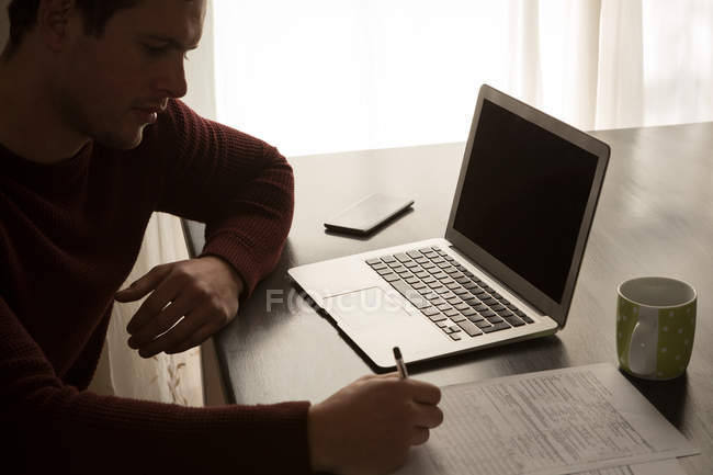 Mann füllt zu Hause ein Formular auf einem Tisch aus — Stockfoto