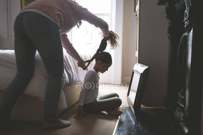 Mère fait une coiffure pour sa fille à la maison — Photo de stock