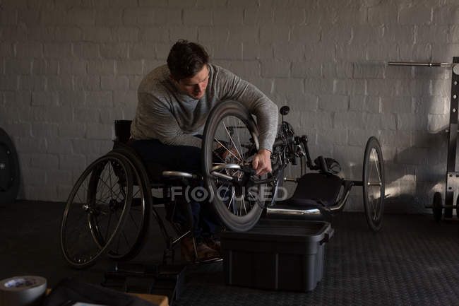 Junger behinderter Mann repariert Rollstuhl in Werkstatt — Stockfoto