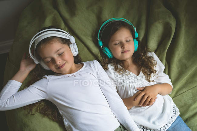 Irmãos ouvindo música enquanto relaxam no quarto em casa — Fotografia de Stock
